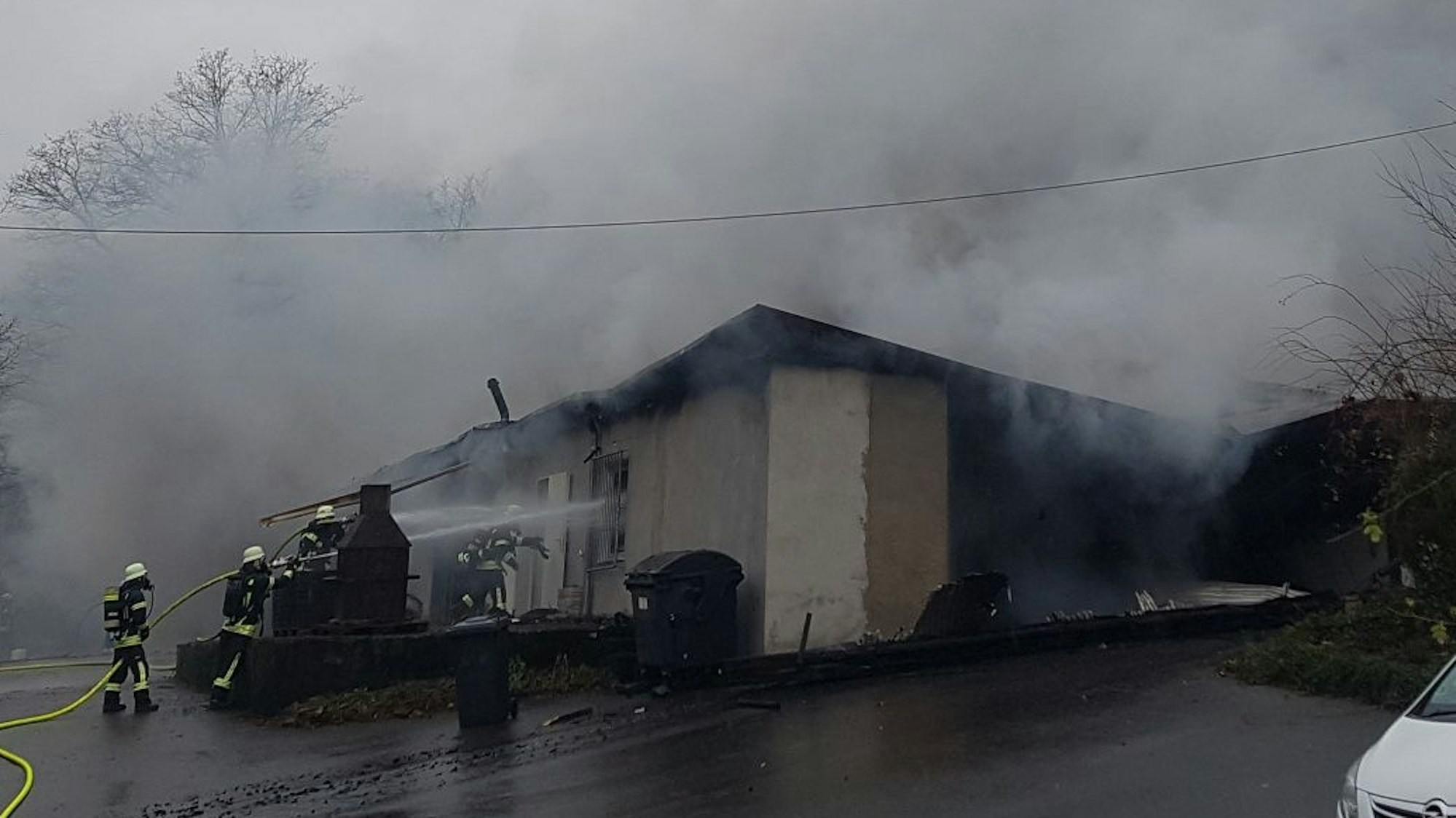 Feuerwehrleute lösche eine Lagerhalle aus der Rauch herausdringt.