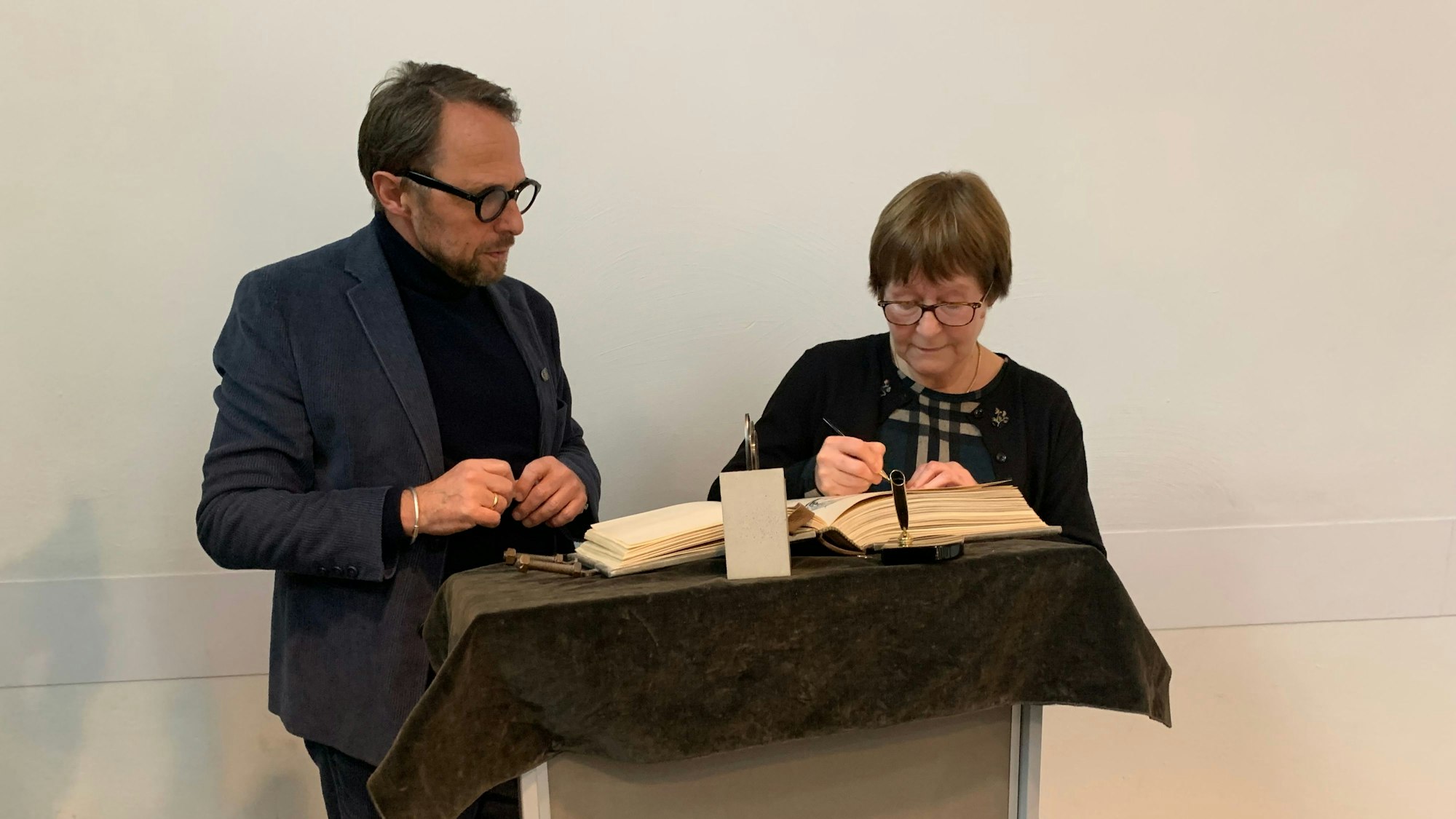 Ein Mann und eine Frau stehen vor einem Pult, auf dem ein Buch liegt.