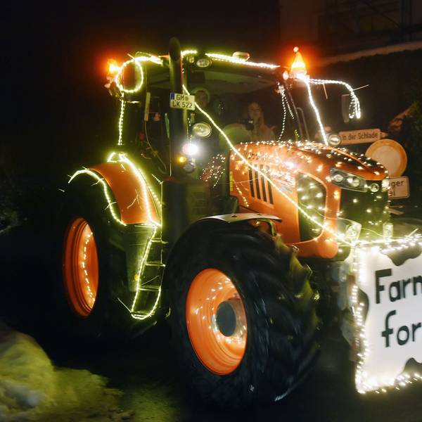 Ein mit Lichterketten geschmückter Trecker. Vorne ist ein Schild angebracht, auf dem steht: „Farmers for Future“.