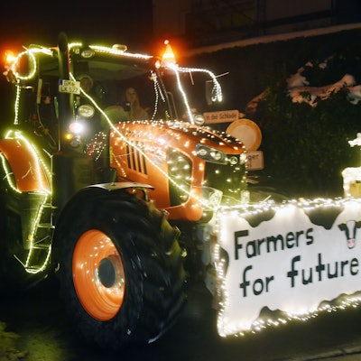 Ein mit Lichterketten geschmückter Trecker. Vorne ist ein Schild angebracht, auf dem steht: „Farmers for Future“.