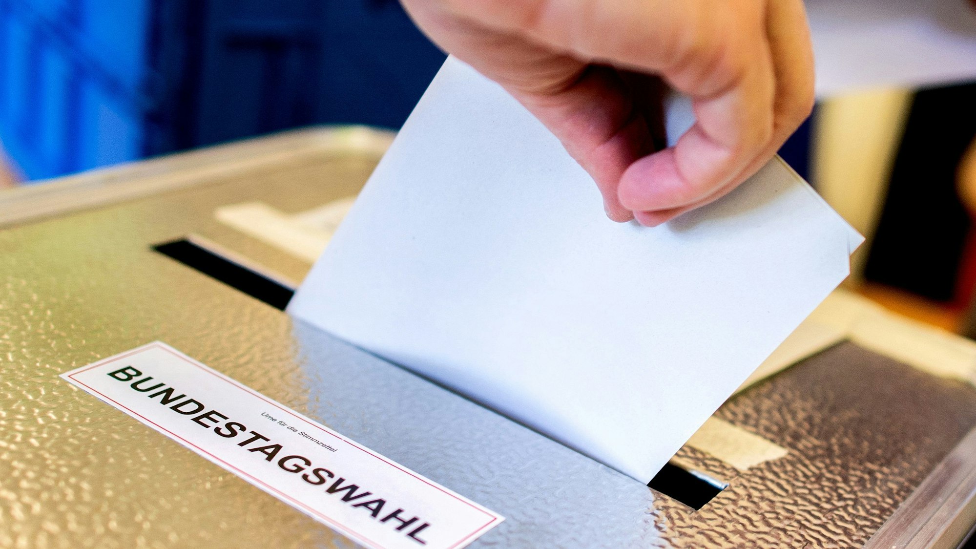 Ein Wähler wirft in einem Wahllokal seinen Stimmzettel für die Bundestagswahl in eine Wahlurne.