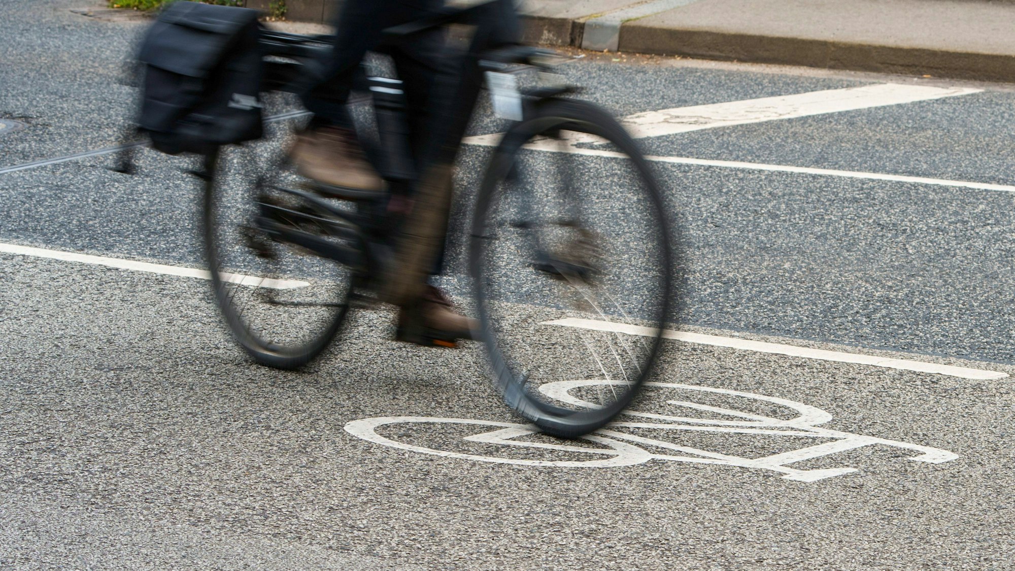 Ein Radfahrer fährt auf einer Straße mit Fahrrad-Piktogramm.