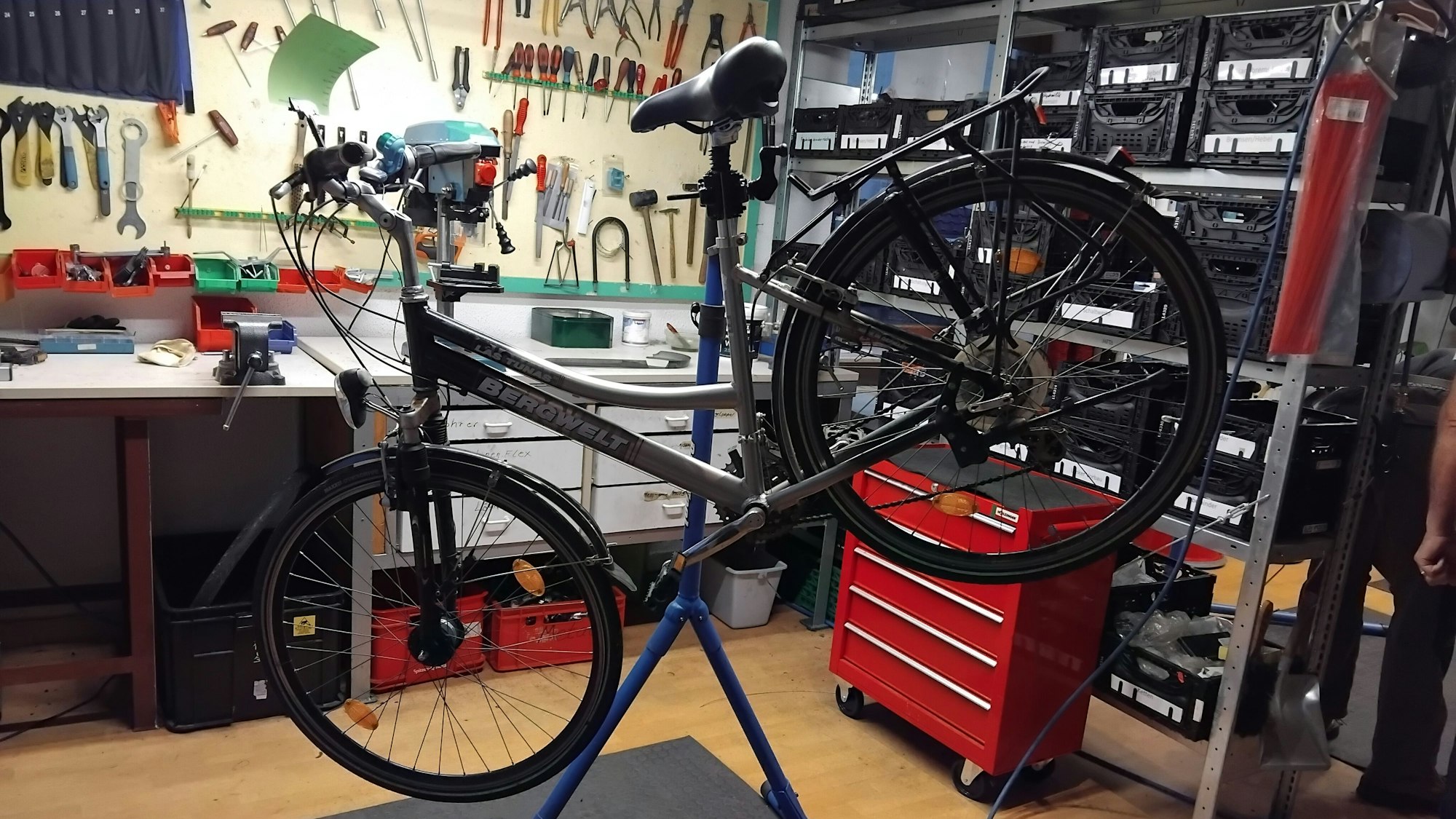 Ein Fahrrad ist zur Reparatur auf einen Ständer gespannt, im Hintergrund sieht man Werkzeug