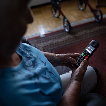 Eine alte Frau guckt auf ein Festnetz-Telefon.