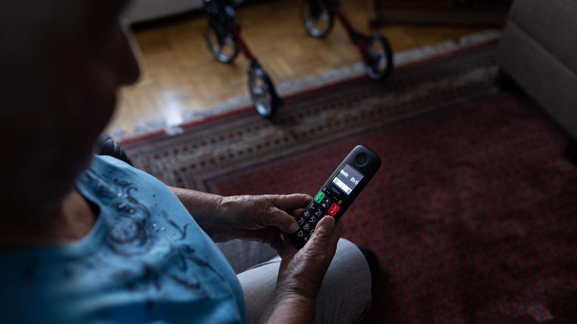 Eine Seniorin schaut auf ihr Telefon.