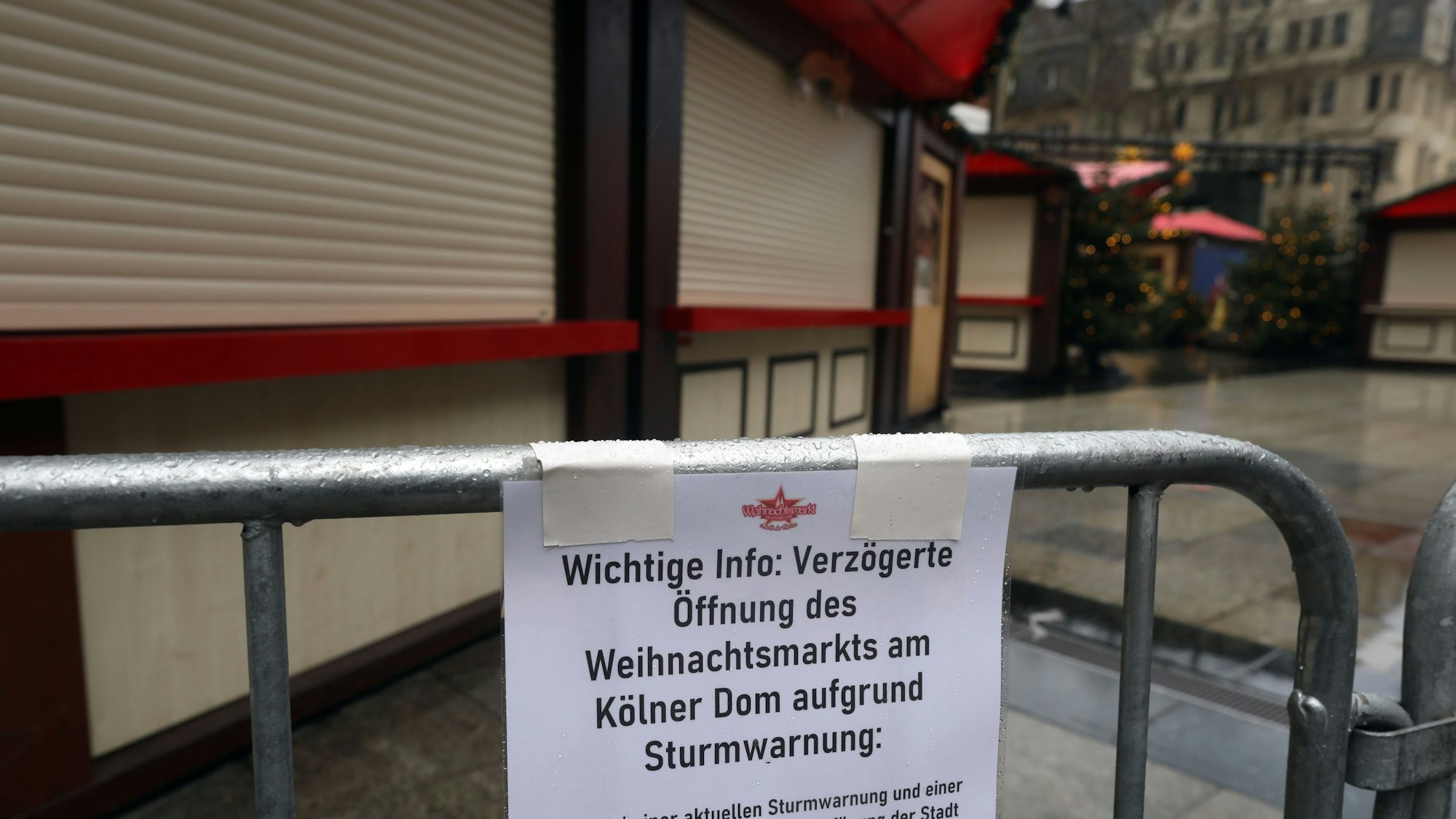 Ein Schild, befestigt an Absperrgittern, informiert über den vorerst geschlossenen Weihnachtsmarkt am Kölner Dom.