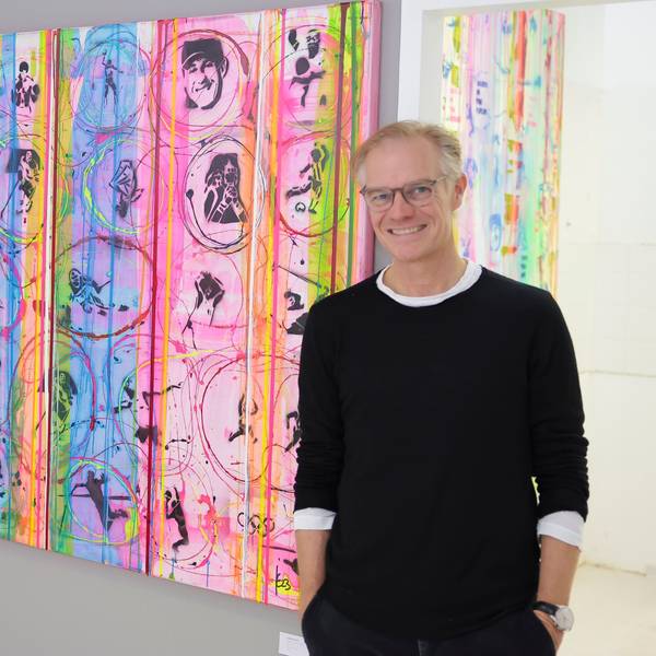 Jens Enneper steht vor einem bunten Gemälde.