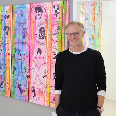 Jens Enneper steht vor einem bunten Gemälde.