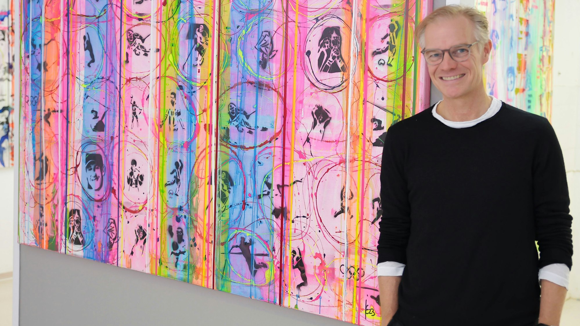 Jens Enneper steht vor einem bunten Gemälde.
