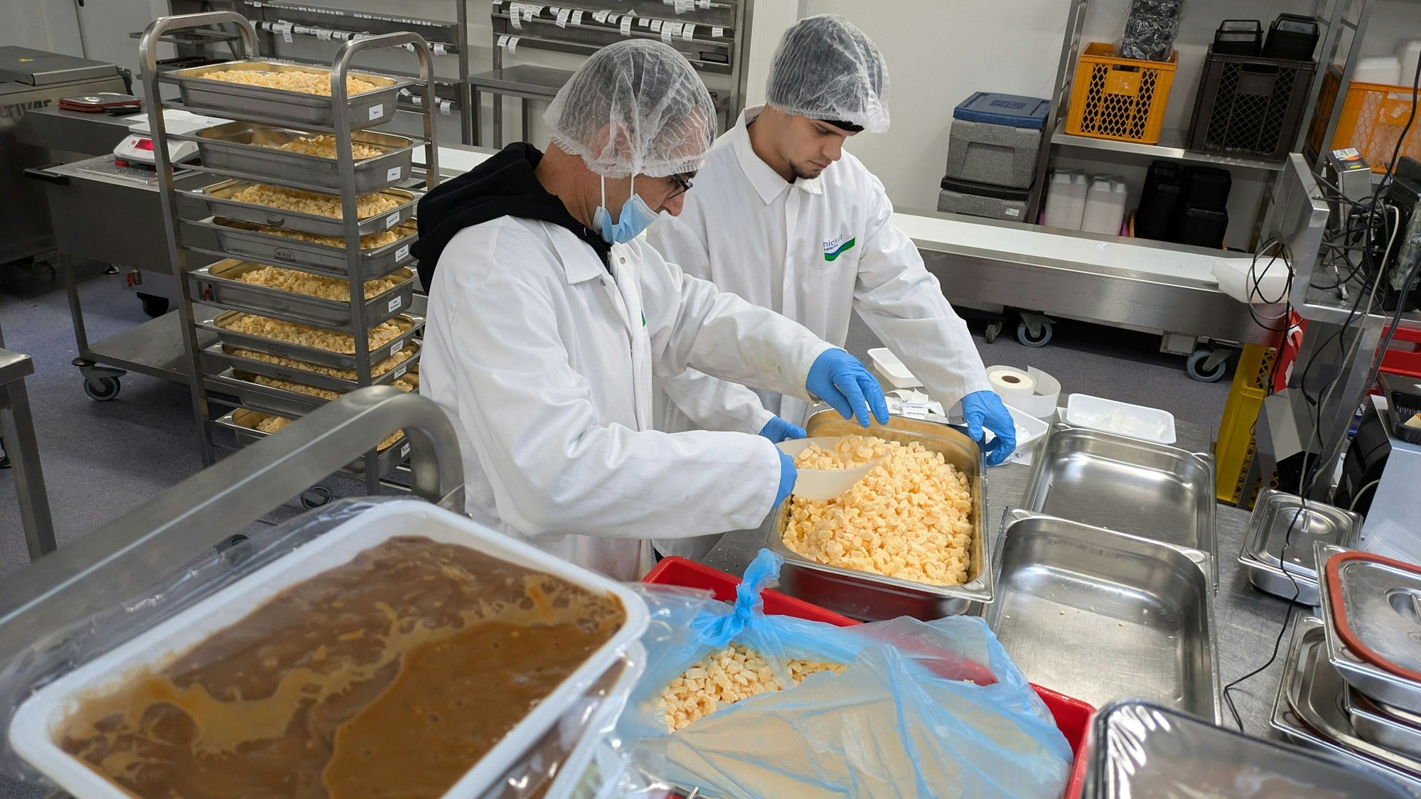 Zwei Männer bereiten in einer Großküche Essen vor.