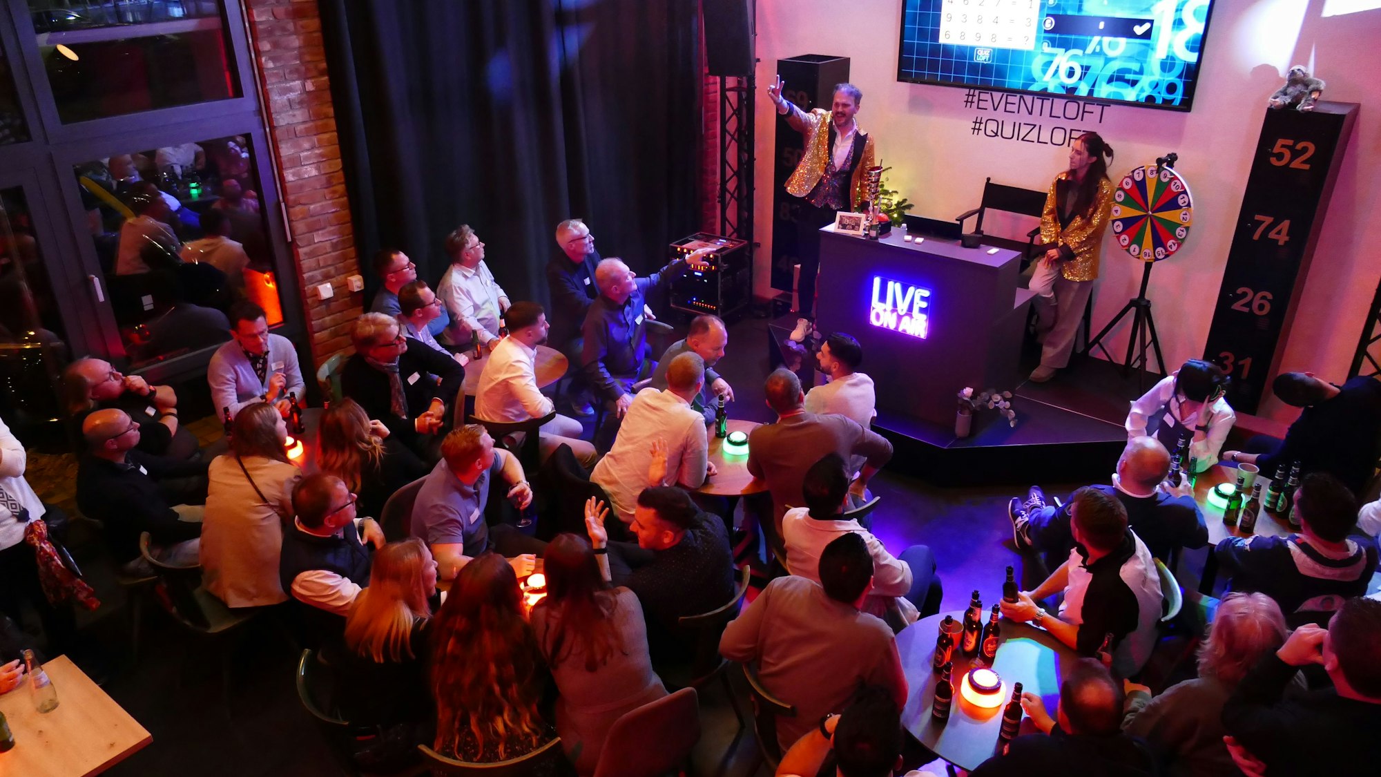 Gäste einer Quizshow in einer Halle.