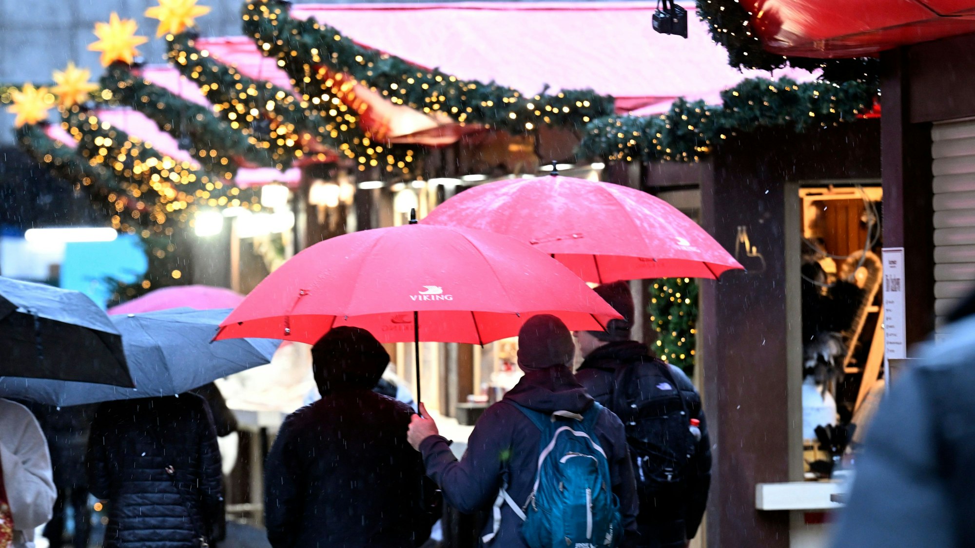 ARCHIV - 19.11.2024, Nordrhein-Westfalen, Köln: Menschen gehen am Weihnachtsmarkt am Dom-Vorplatz in Köln mit Schirmen durch den Regen. (zu dpa: «Reul: Weiterhin keine Hinweise auf Anschlagspläne») Foto: Roberto Pfeil/dpa +++ dpa-Bildfunk +++