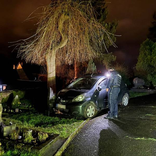Ein Auto steht nachts auf einem Friedhof, ein Polizist daneben.