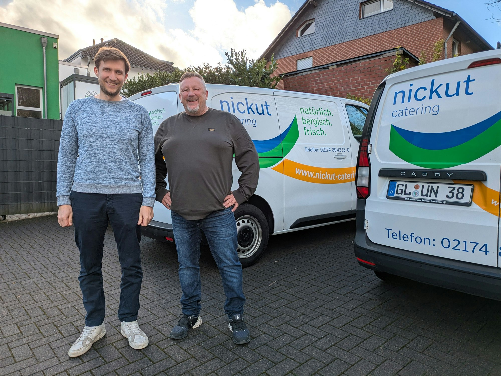 Zwei Männer stehen vor Lieferwagen.