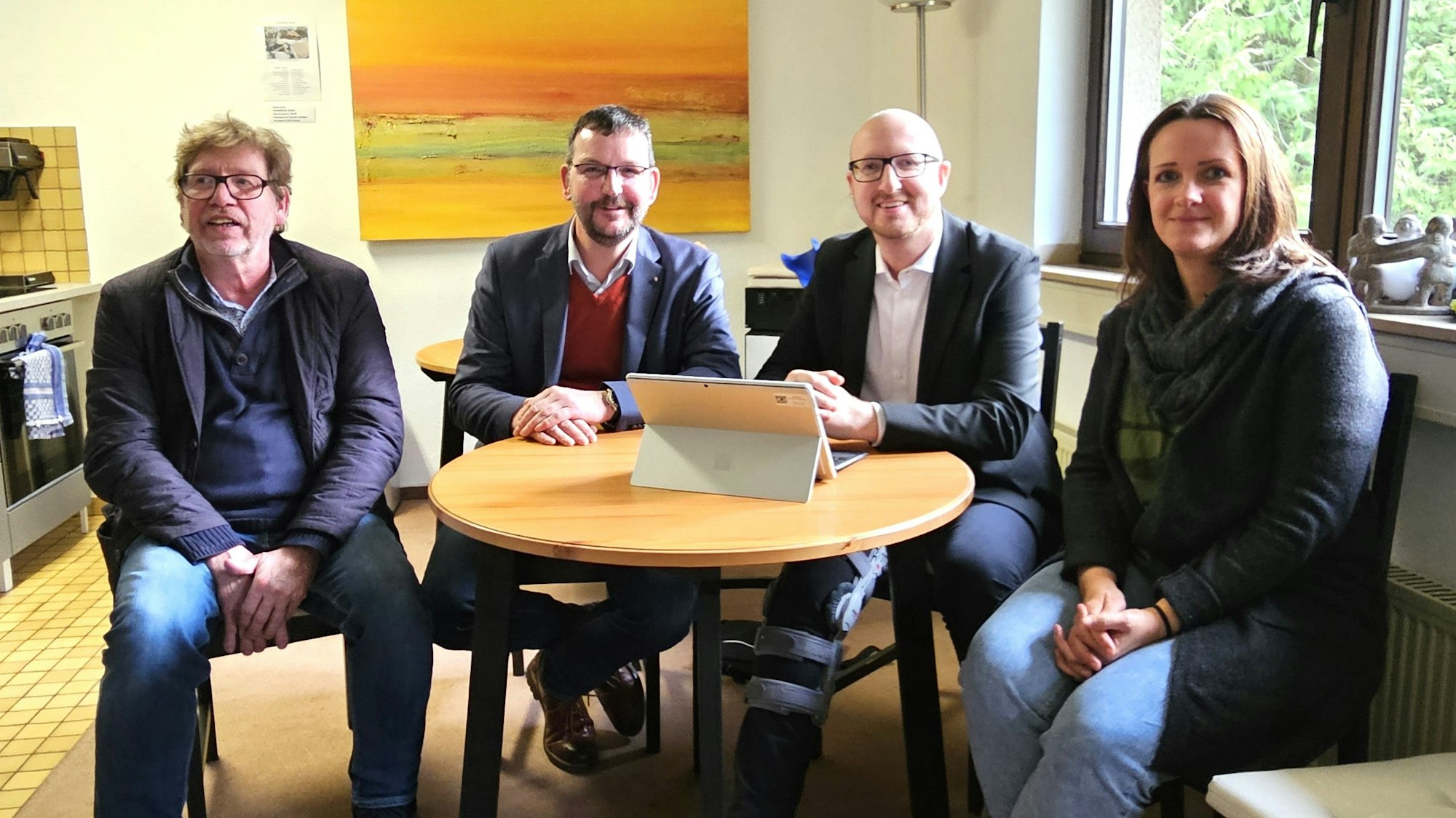 Frank Waldschmidt, Wolfgang Heidinger, Ingo Pfennings und Michaela Kratz sitzen nebeneinander mit einem Tisch, auf dem ein Laptop steht.