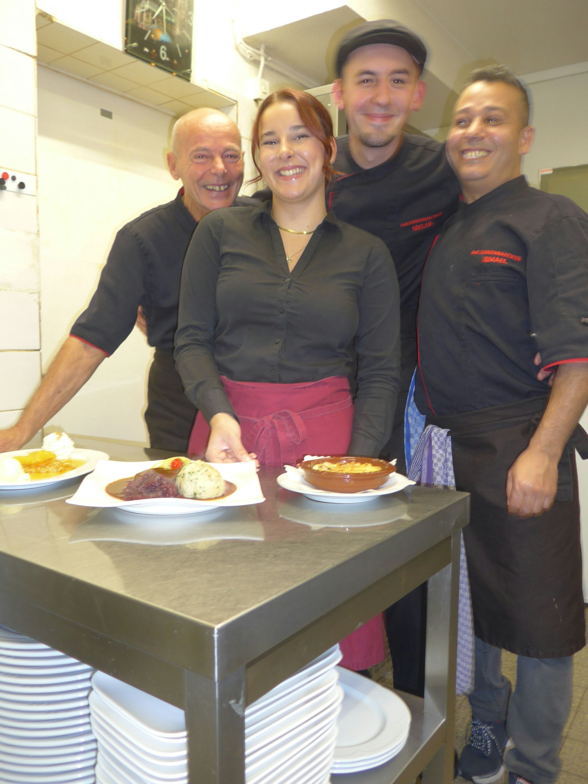 Auf dem Bild sind das Küchenteam und die drei Gerichte des Menüs zu sehen.