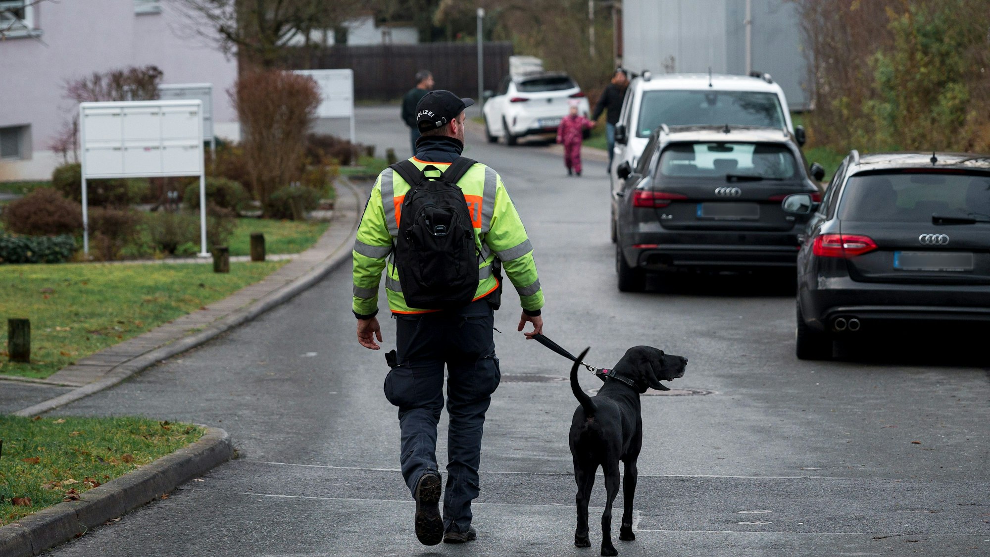 Ein Polizist geht mit einem Personenspürhund durch ein Wohngebiet. (Symbolbild)