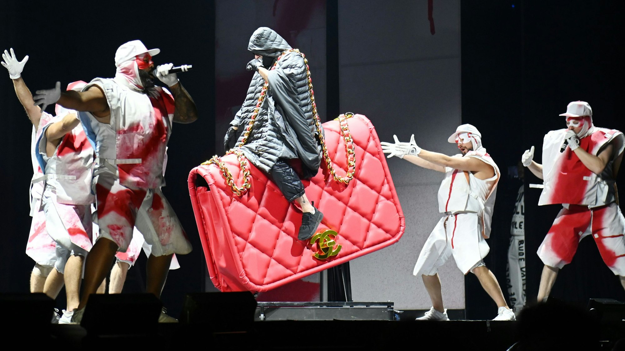 Kryptik Joe, das einzig verbliebene Original-Mitglied von Deichkind, reitet bei ihrer Show in Köln eine rote Chanel-Tasche.