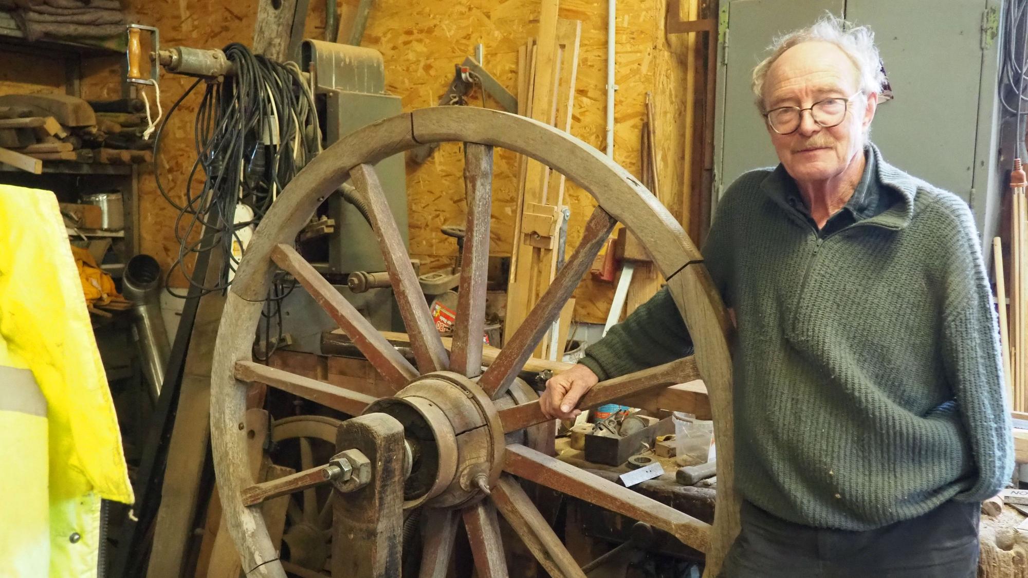 Das Foto zeigt den Stellmacher Walter Keil in seiner Werkstatt mit einem hölzernen Rad.