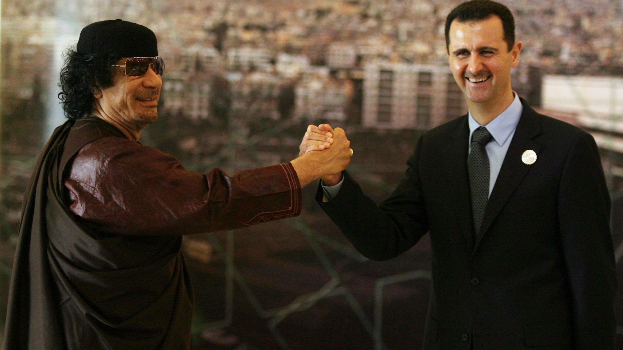 Bashar al-Assad (r.) und Moamer Kadhafi geben sich die Hand.