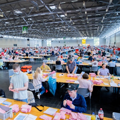 Wahlhelferinnen und Wahlhelfer öffnen bei der Auszählung der Briefwahl zur Bundestagswahl in der Messehalle 6 die rosafarbenen Umschläge. +++ dpa-Bildfunk +++