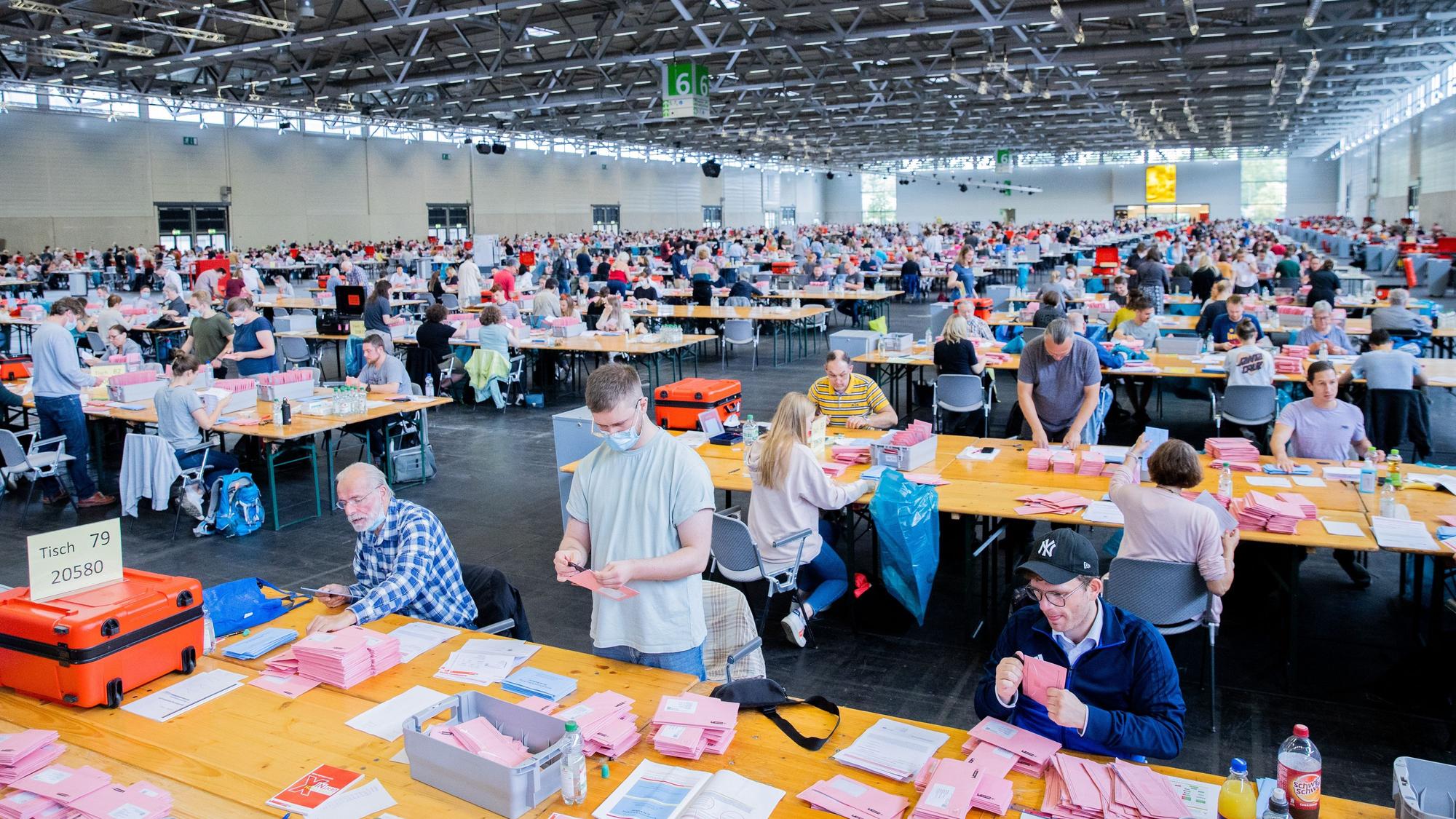 Wahlhelferinnen und Wahlhelfer öffnen bei der Auszählung der Briefwahl zur Bundestagswahl in der Messehalle 6 die rosafarbenen Umschläge. +++ dpa-Bildfunk +++
