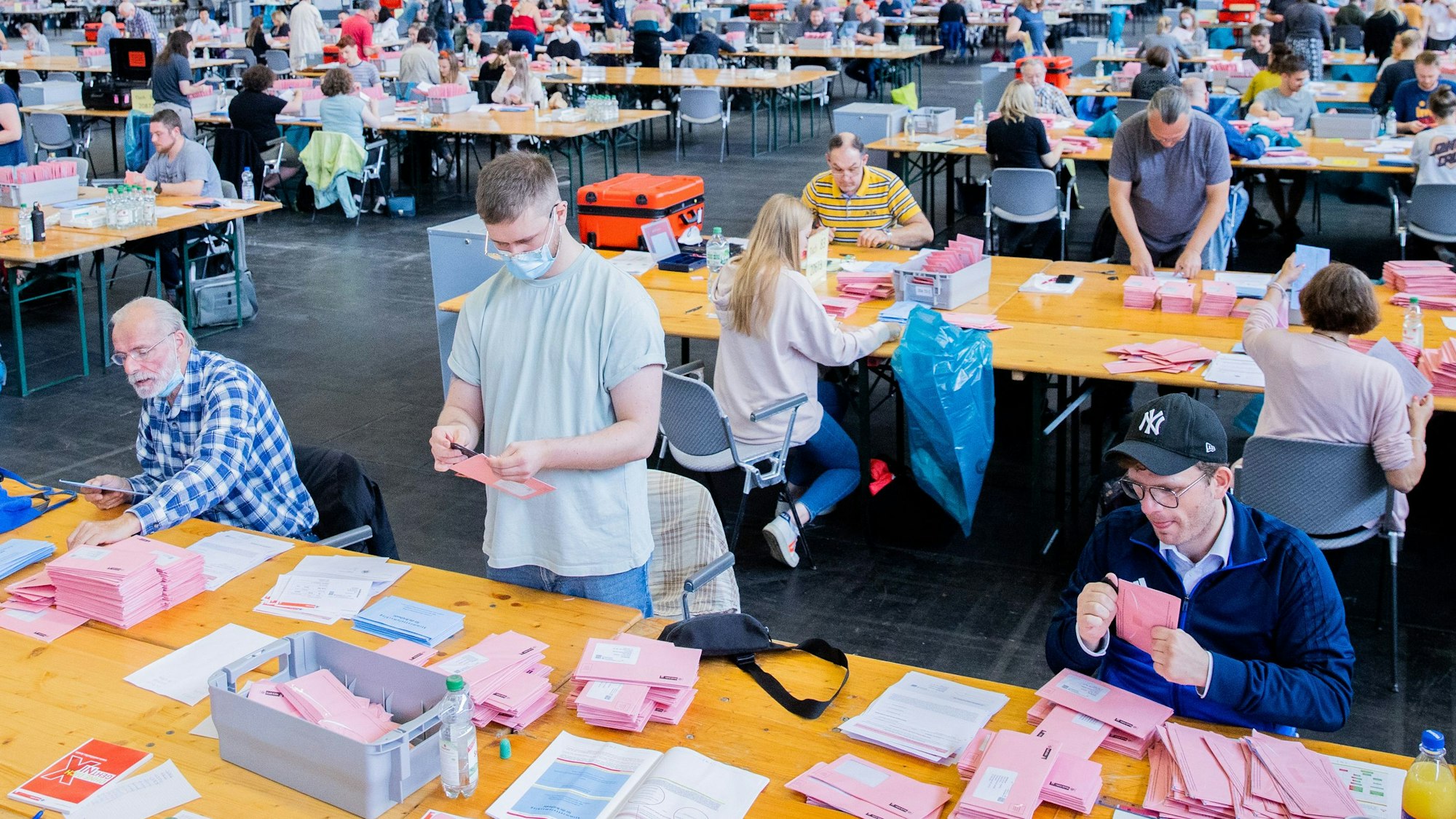 Wahlhelferinnen und Wahlhelfer öffnen bei der Auszählung der Briefwahl zur Bundestagswahl in der Messehalle 6 die rosafarbenen Umschläge. +++ dpa-Bildfunk +++