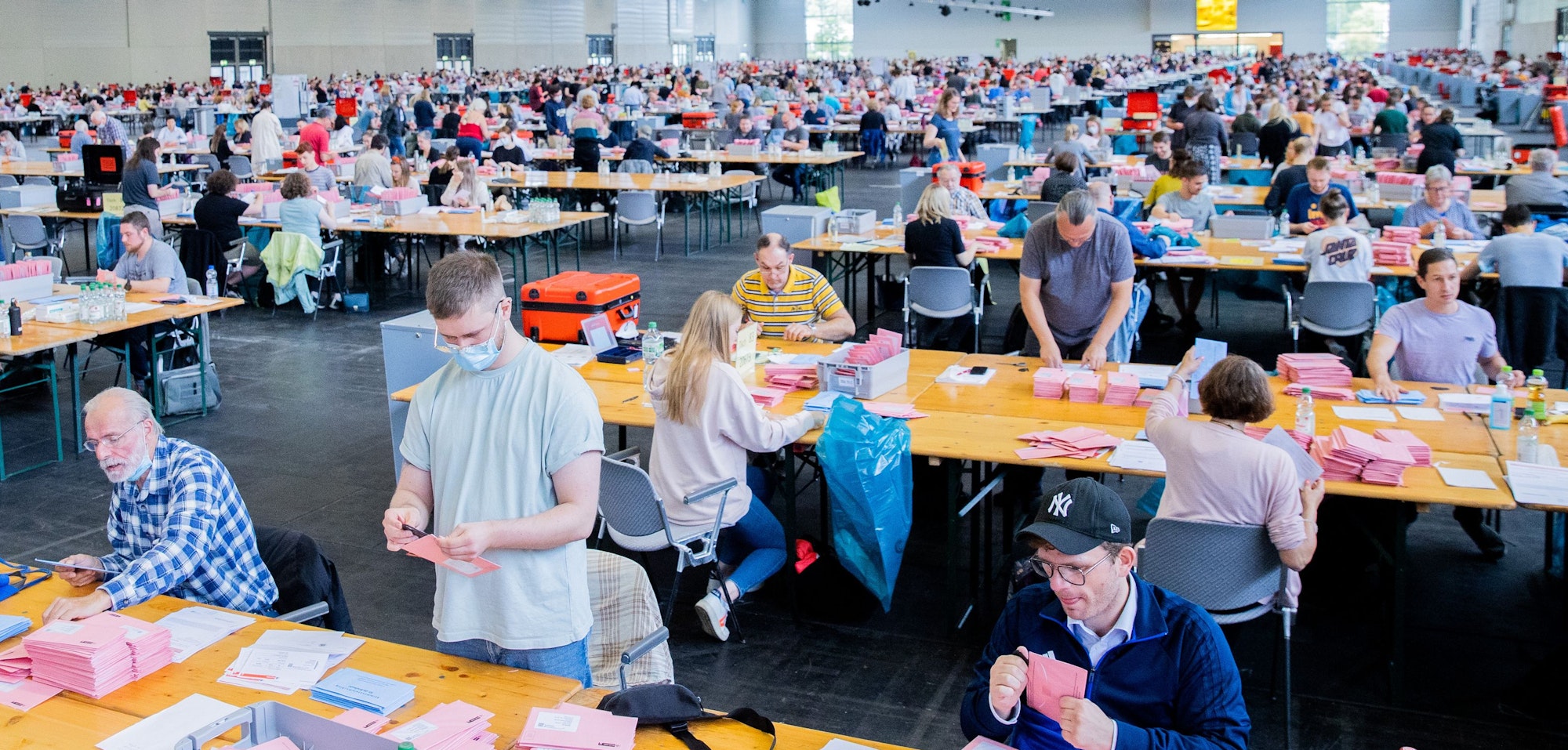Wahlhelferinnen und Wahlhelfer öffnen bei der Auszählung der Briefwahl zur Bundestagswahl in der Messehalle 6 die rosafarbenen Umschläge.