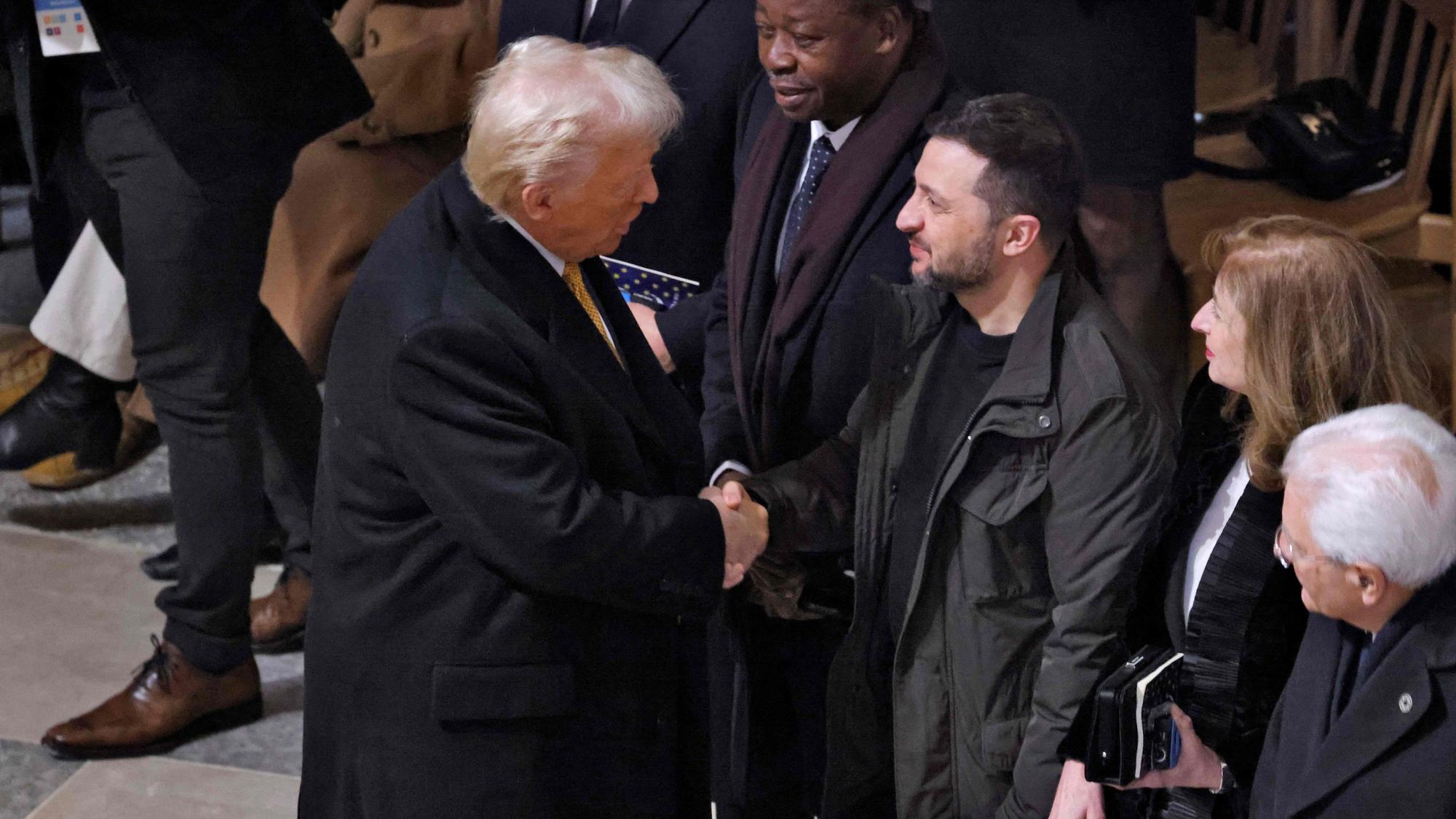 Donald Trump begrüßt Wolodymyr Selenskyj in Paris und schüttelt ihm die Hand.