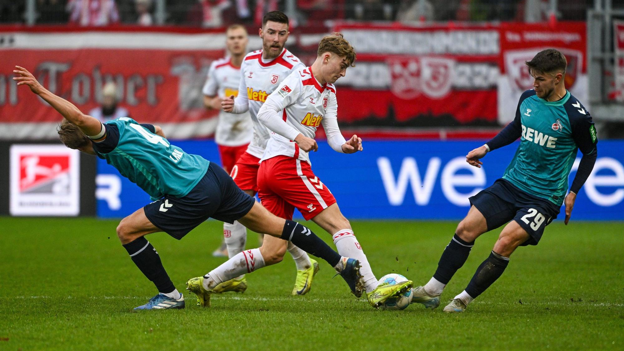 08.12.2024, Bayern, Regensburg: Fußball: 2. Bundesliga, Jahn Regensburg - 1. FC Köln, 15. Spieltag, Jahnstadion Regensburg. Timo Hübers von Köln (l-r), Dominik Kother von Regensburg und Jan Thielmann von Köln kämpfen um den Ball. Foto: Armin Weigel/dpa - WICHTIGER HINWEIS: Gemäß den Vorgaben der DFL Deutsche Fußball Liga bzw. des DFB Deutscher Fußball-Bund ist es untersagt, in dem Stadion und/oder vom Spiel angefertigte Fotoaufnahmen in Form von Sequenzbildern und/oder videoähnlichen Fotostrecken zu verwerten bzw. verwerten zu lassen. +++ dpa-Bildfunk +++