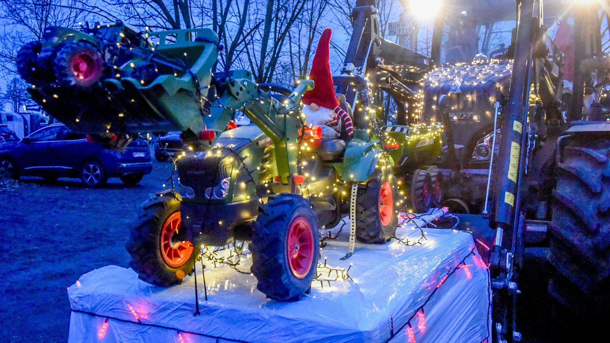 Ein Miniatur-Nikolaus, der Traktor fährt, auf der Gabel eines Traktors, gefahren vom Nikolaus.