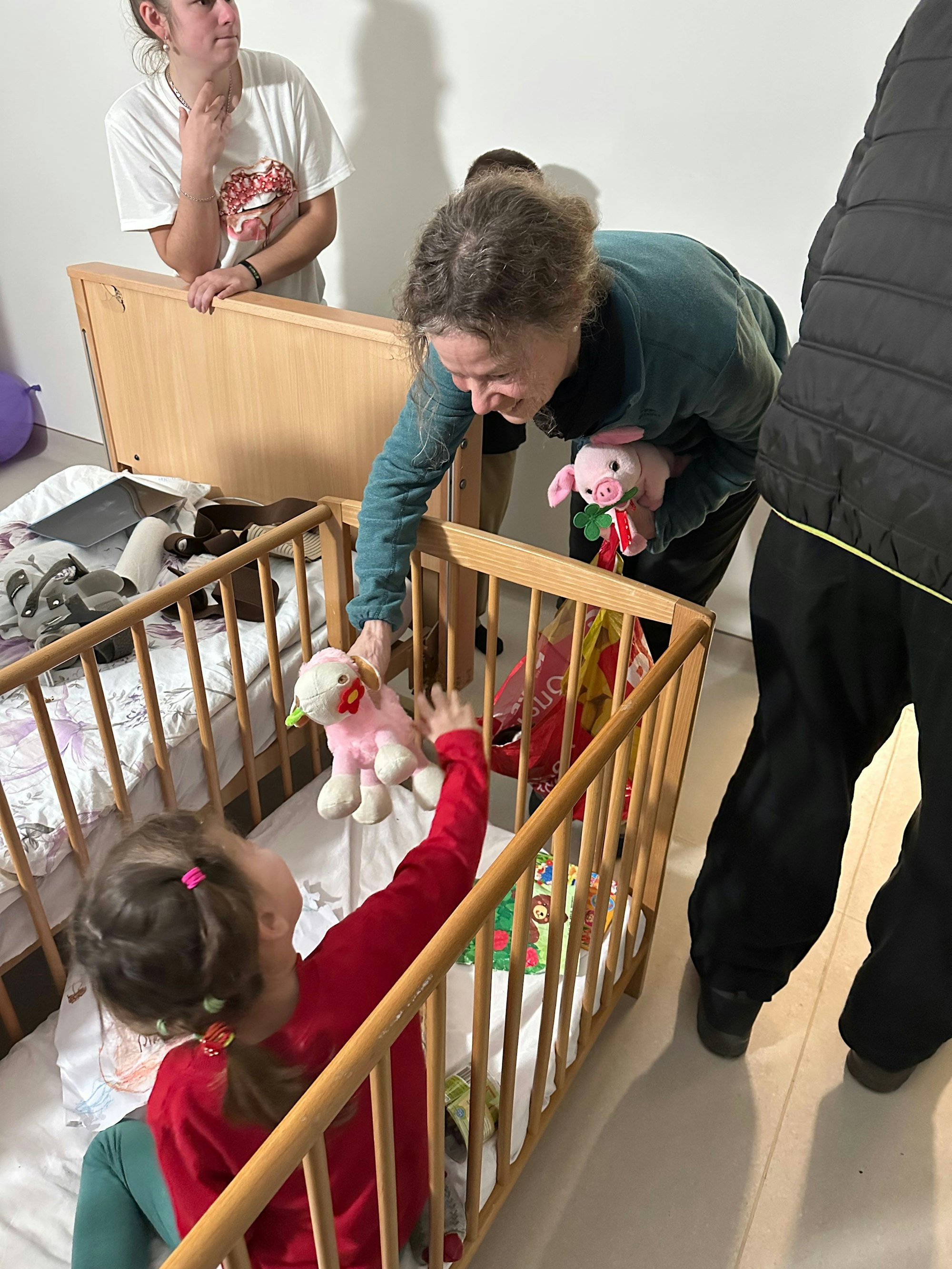 Susann Meurer beugt sich zu einem Kind in einem Gitterbett in der Kinderklinik von Lviv/Ukraine hinunter.