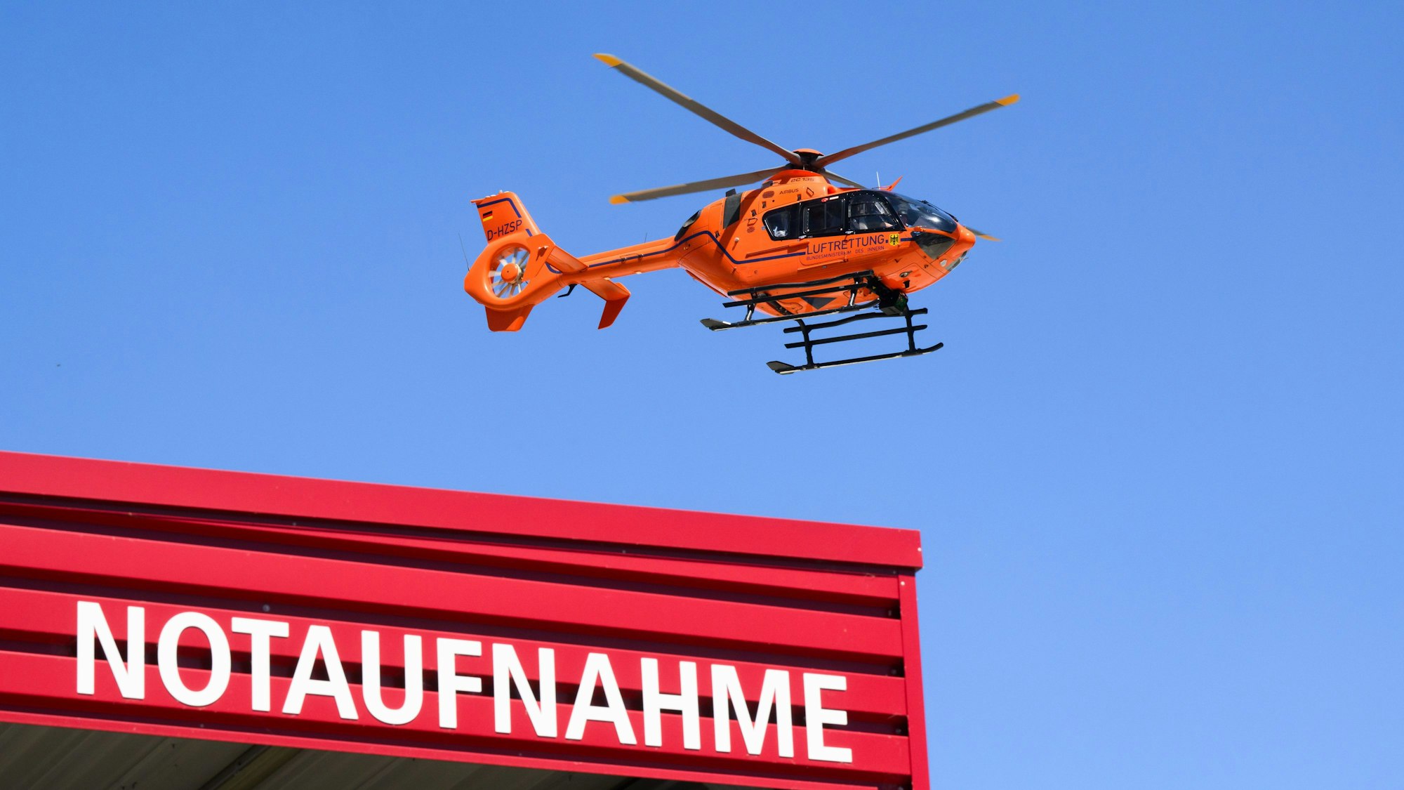 Ein Rettungshubschrauber fliegt über einer Notaufnahme.