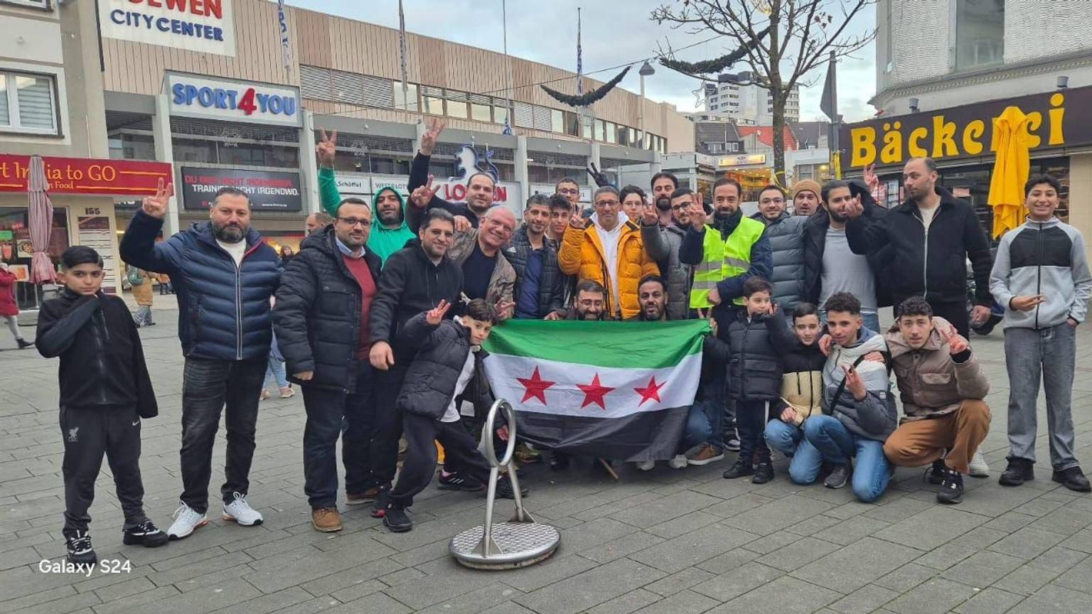 In Bergisch Gladbach feierten syrische Geflüchtete in der Fußgängerzone den Sturz von Assad und halten eine syrische Flagge in der Hand.