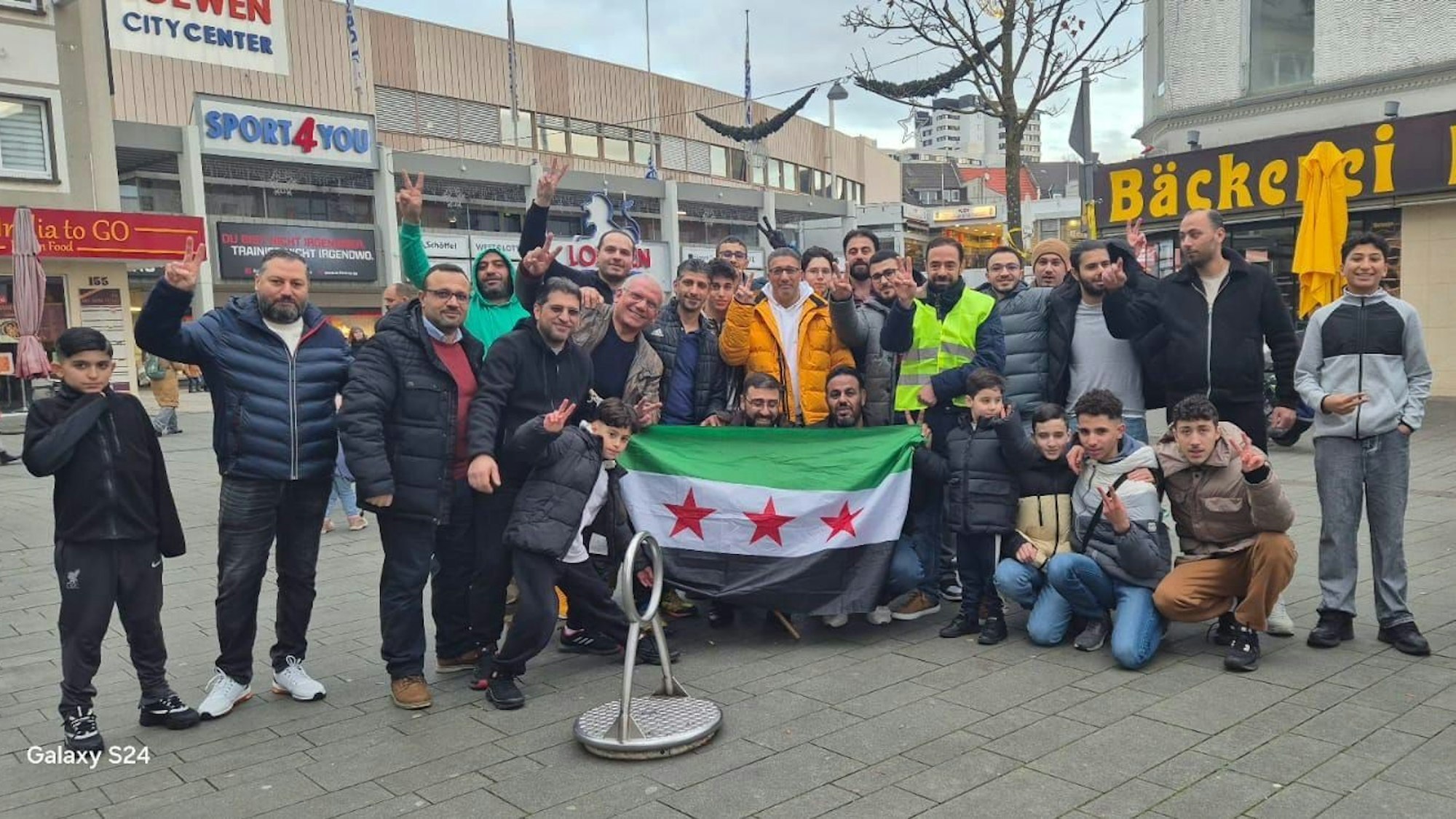In Bergisch Gladbach feierten syrische Geflüchtete in der Fußgängerzone den Sturz von Assad und halten eine syrische Flagge in der Hand.
