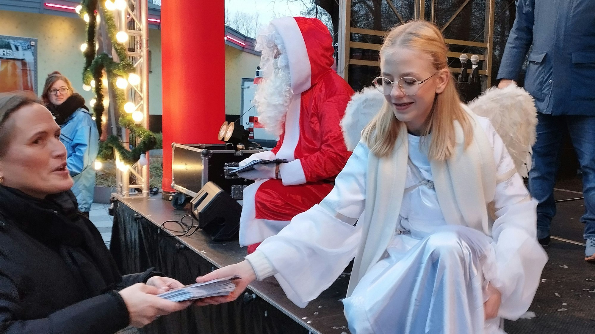 Ein als Engel verkleidetes Mädchen verteilt das Liederheft zum Bergheimer Nikolaussingen.