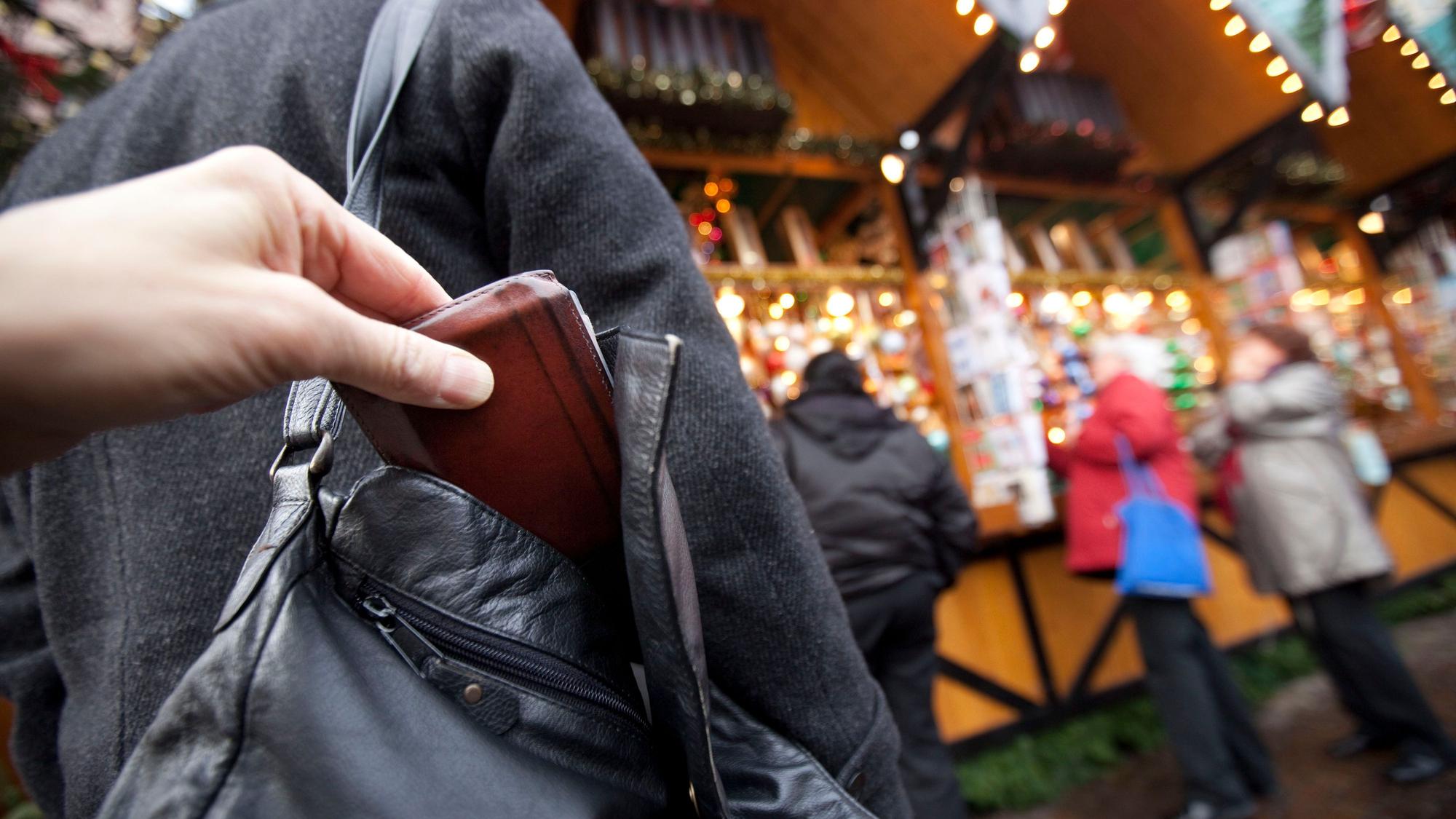 Ein Mann zieht auf dem Weihnachtsmarkt einer Besucherin die Geldbörse aus der Handtasche.