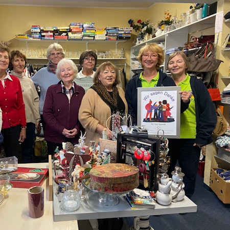 Neun Damen stehen nebeneinander in einem Raum. Eine hält ein Plakat mit der Aufschrift Wir sagen Danke.