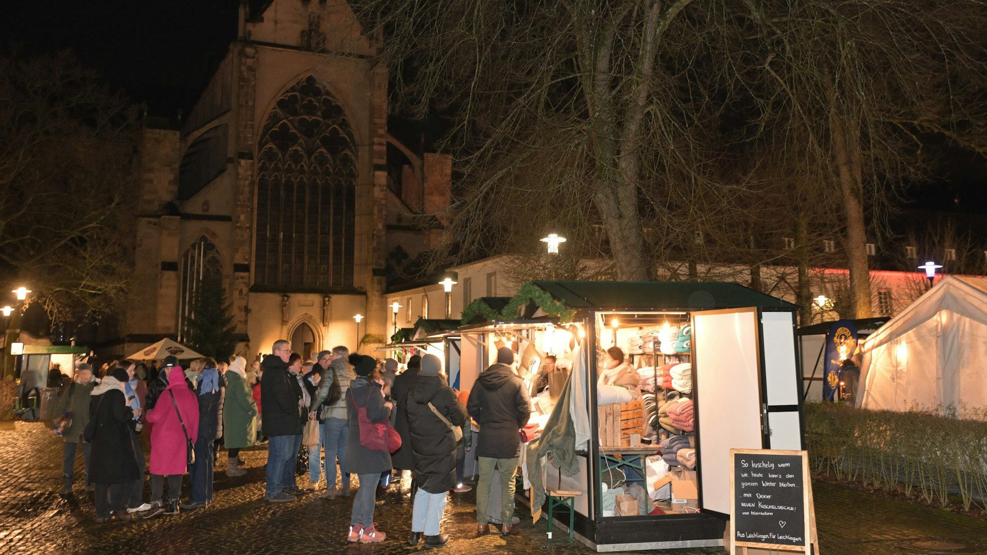 Beleuchtete Buden des Adventsmarkts stehen vor dem Altenberger Dom.
