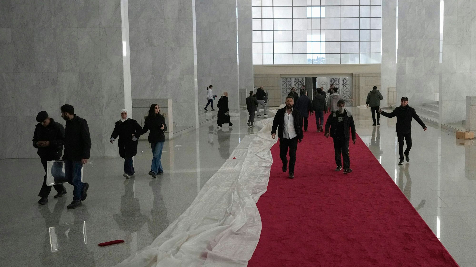 Menschen laufen durch eine riesige Empfangshalle des syrischen Präsidenten.