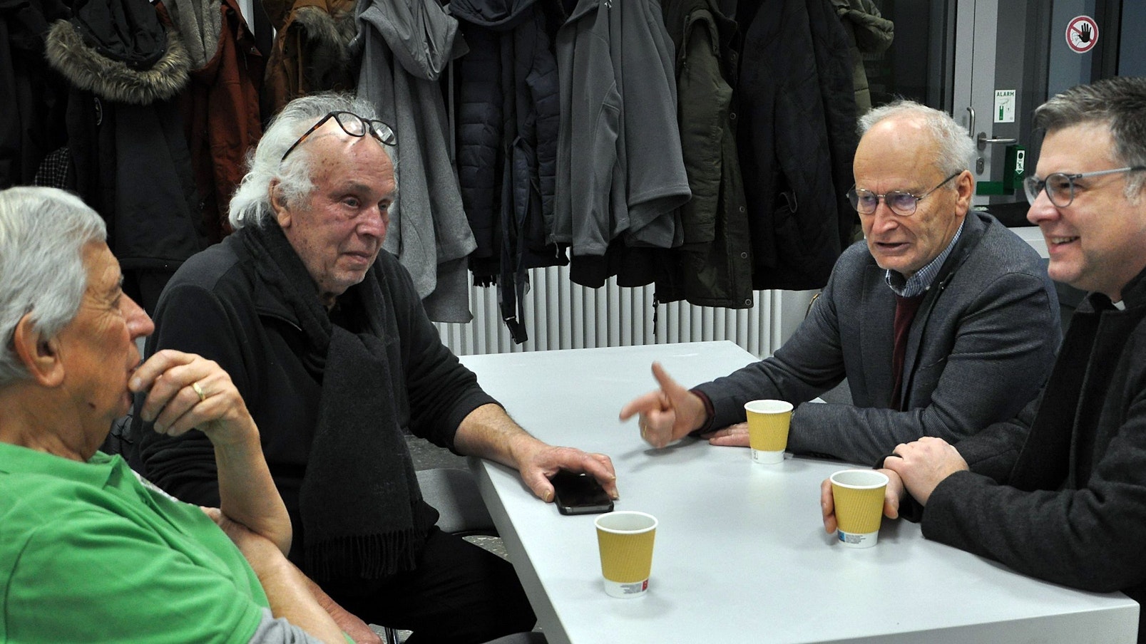 Vier Männer sitzen an einem Tisch und unterhalten sich.