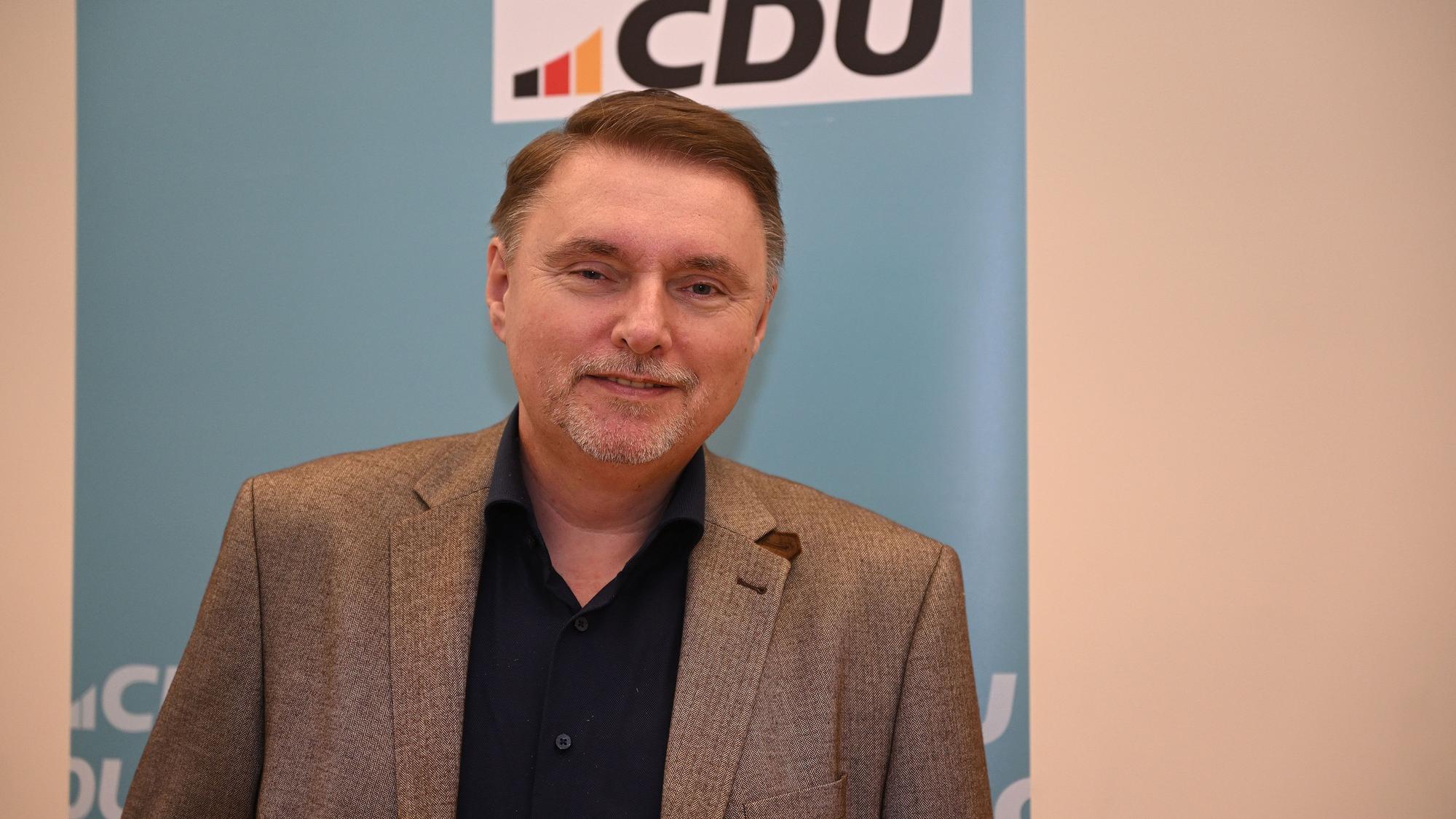 CDU-Bürgermeisterkandidat Michael Eyer steht vor einer CDU-Wand in Overath.