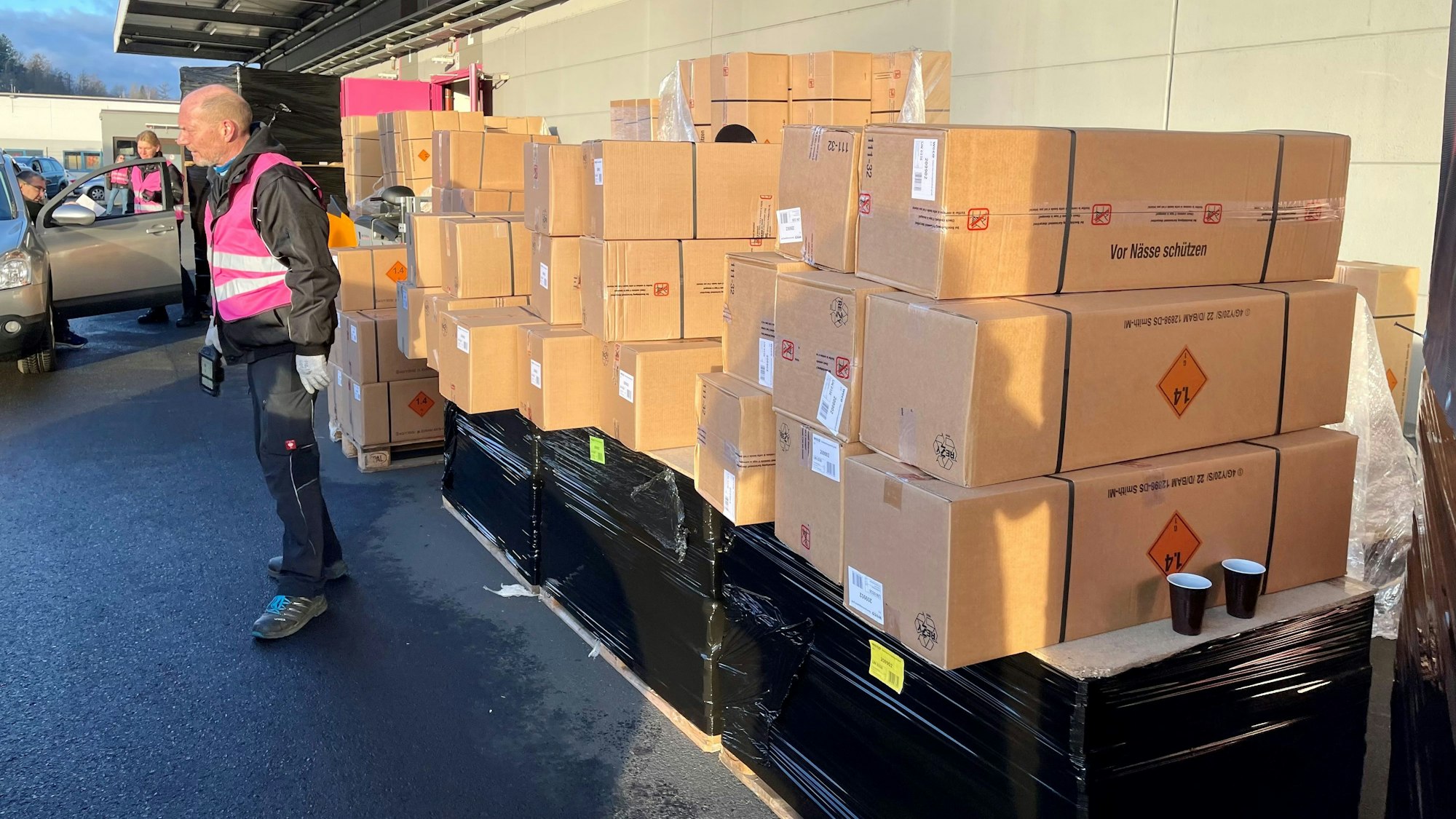 Viele lange Pakete sind an einer Wand hochgestapelt.