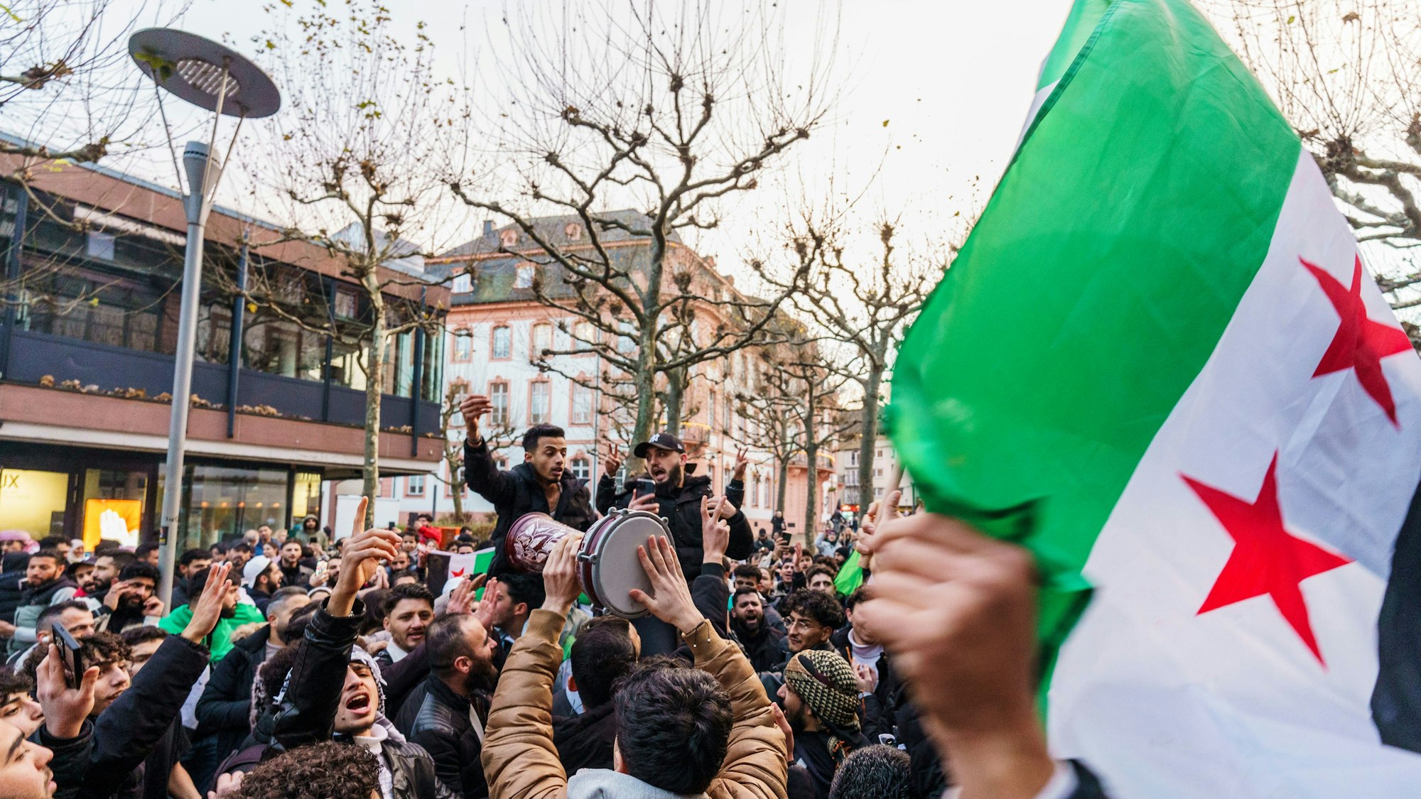 Exil-Syrer feiern in Mainz den Sturz des Assad-Regimes und schwenken dabei die syrische Nationalflagge.