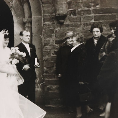 Ein Hochzeitspaar vor der Kirche in Waldbröl. Das Foto ist ein altes schwarz-weißes Foto.