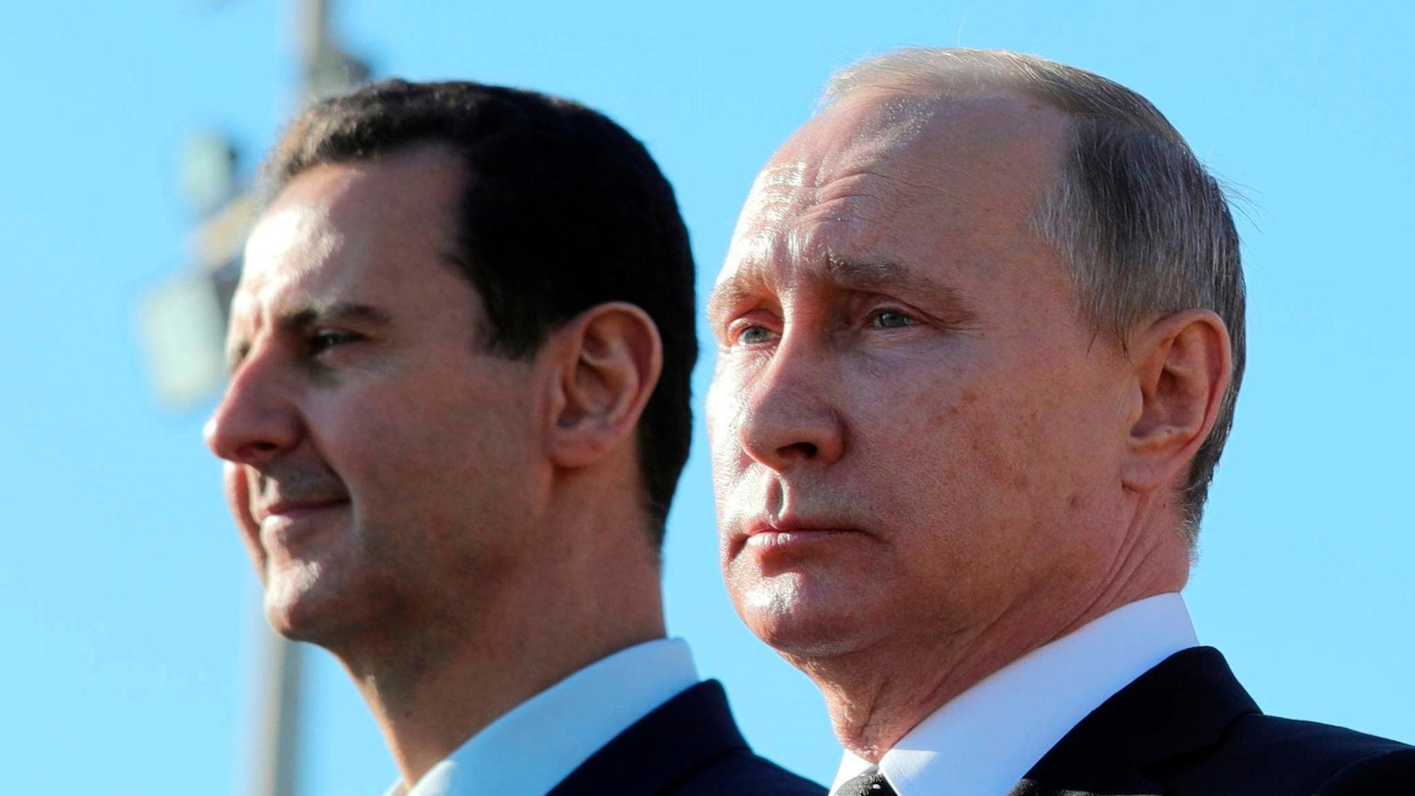 FILE - Russian President Vladimir Putin, right, and Syrian President Bashar Assad watch troops marching at the Hemeimeem air base in Syria, on Dec. 11, 2017. (Mikhail Klimentyev, Sputnik, Kremlin Pool Photo via AP, File)