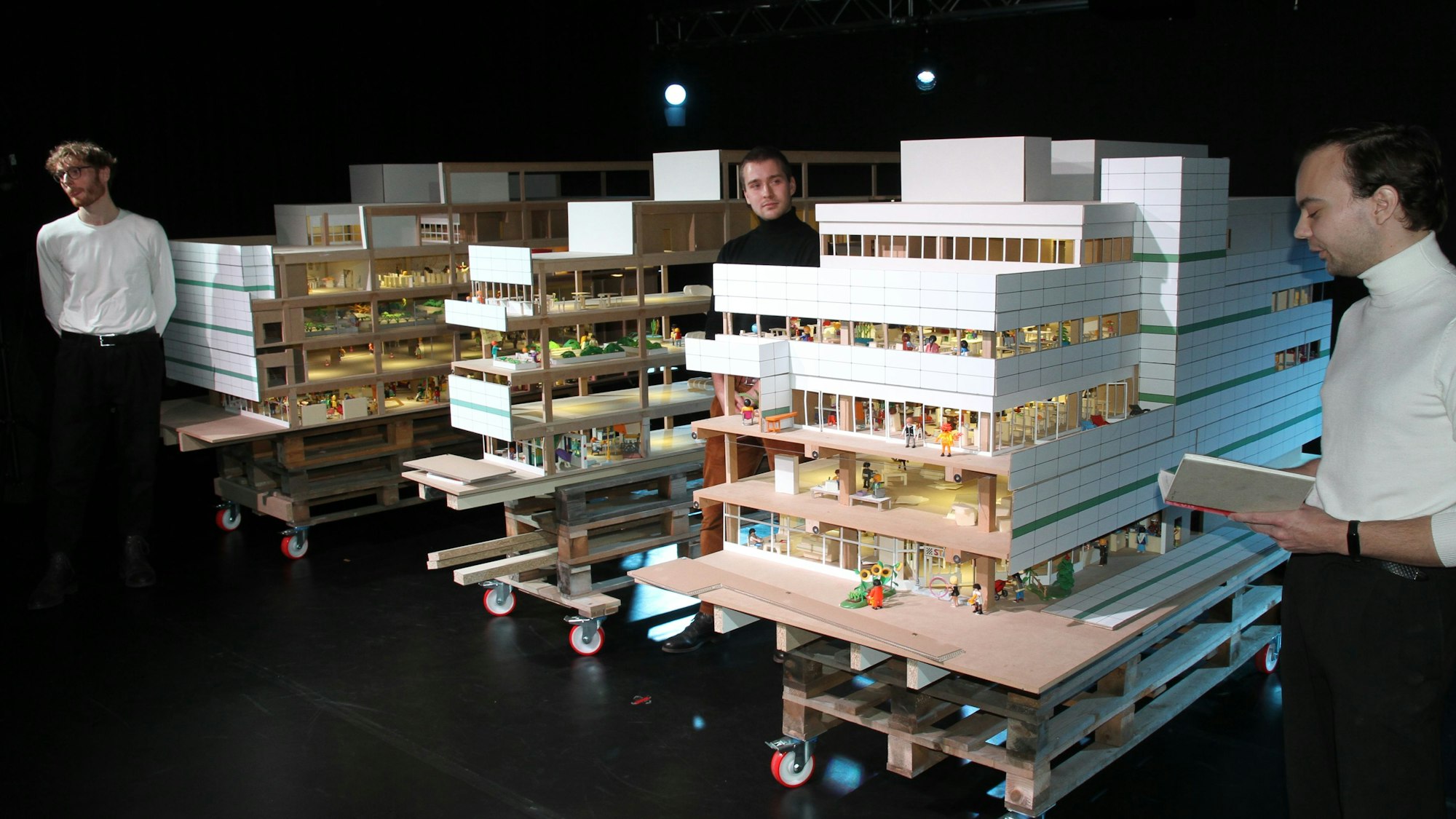 Drei Studenten mit dem Modell eines Kaufhauses.