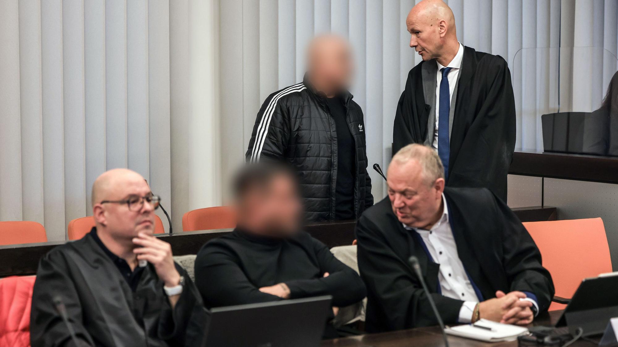 dpatopbilder - 10.12.2024, Nordrhein-Westfalen, Wuppertal: Der Hauptangeklagte (hinten, links) spricht im Gerichtssaal mit seinem Verteidiger Oliver Doelfs (hinten, rechts), während vorne ein Angeklagter (M) mit seinem Verteidiger Hartmut Moyzio (vorne, rechts) spricht. In Wuppertal hat der Prozess wegen eines Erpressungsversuchs gegen die Familie von Ex-Formel-1-Weltmeister Michael Schumacher begonnen. Angeklagt sind drei 30 bis 53 Jahre alte Männer. Dem Haupttäter wird versuchte Erpressung in einem besonders schweren Fall vorgeworfen, den beiden anderen Beihilfe dazu. Foto: Oliver Berg/dpa - ACHTUNG: Person(en) wurde(n) aus rechtlichen Gründen gepixelt +++ dpa-Bildfunk +++