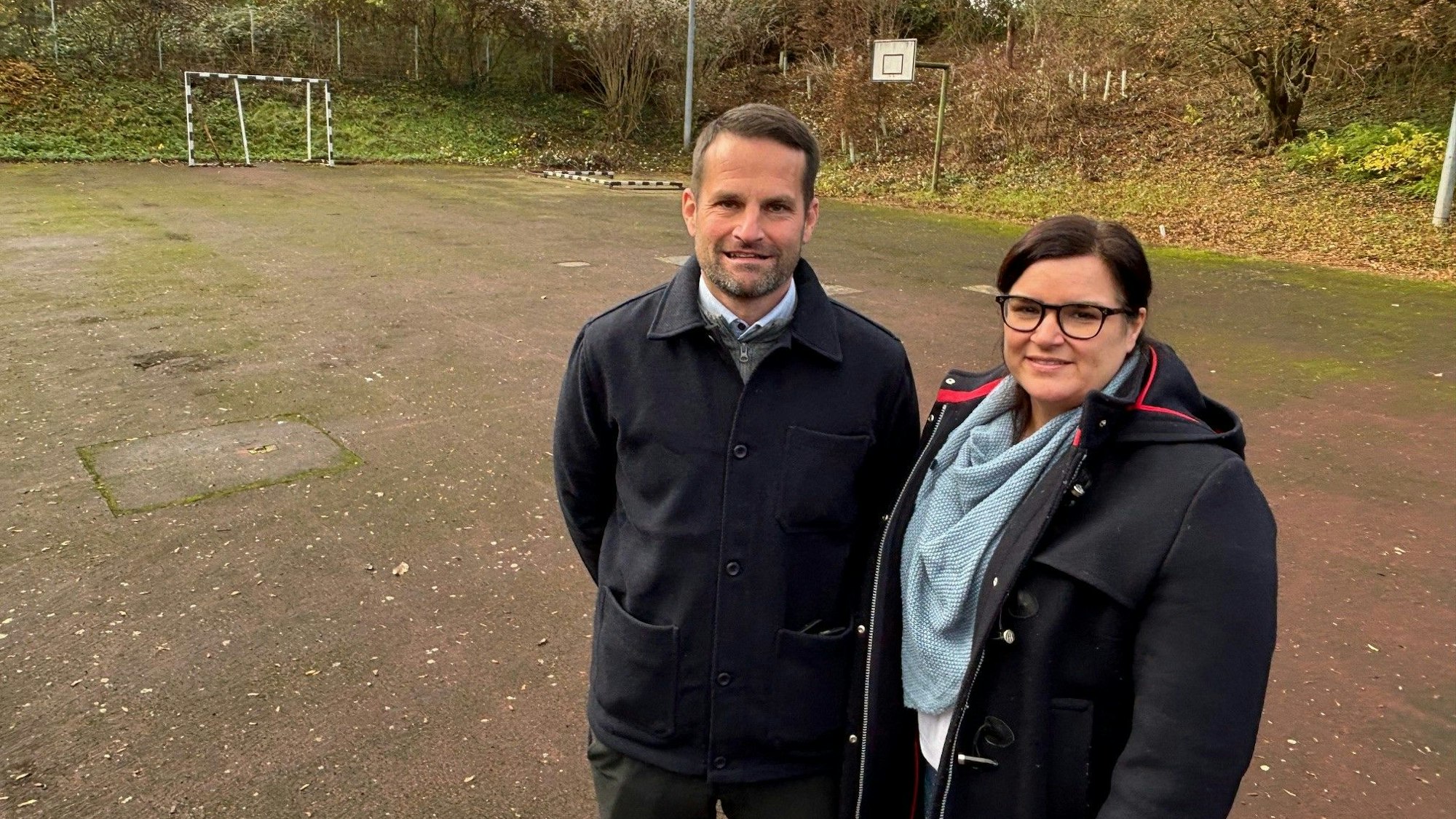 Auf dem Bild sind ein Mann und eine Frau auf dem alten Sportplatz zu sehen, sie organisieren die Kampagne.