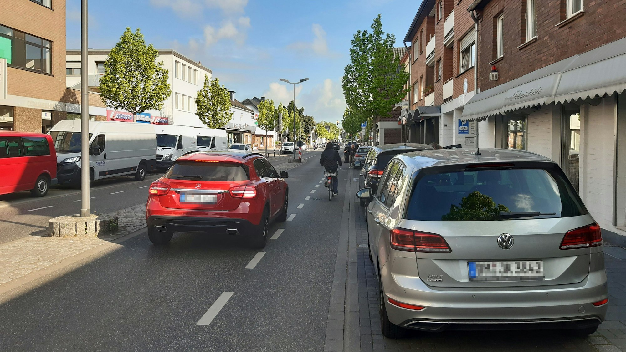 Das Foto zeigt einen Radfahrer, der vor einem Auto auf der Straße fährt.